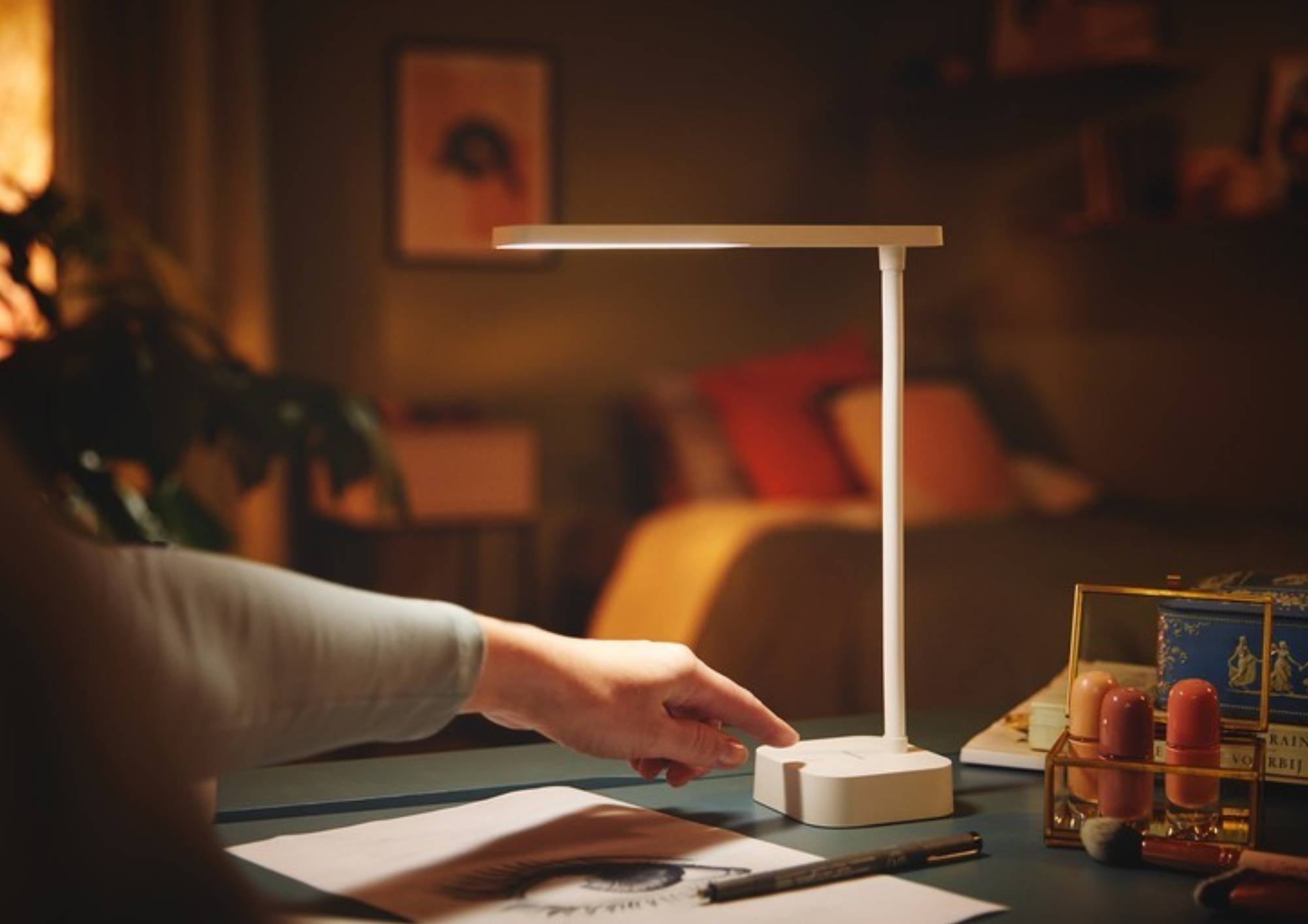 Ruka zapínající stolní lampu stojící na pracovním stole