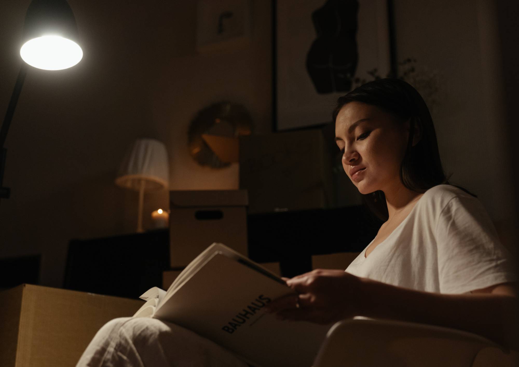 Žena čtoucí knihu při zapnutém světle v tlumeném interiéru